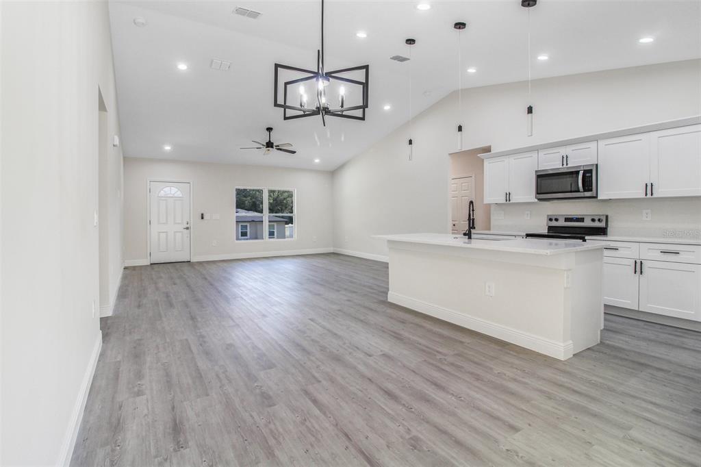 406 Ruby Avenue Deland, FL 32724 - Photo 3 of 23 a kitchen with kitchen island white cabinets and wooden floor