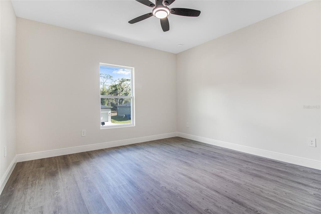 406 Ruby Avenue Deland, FL 32724 - Photo 5 of 23 an empty room with wooden floor chandelier fan and windows