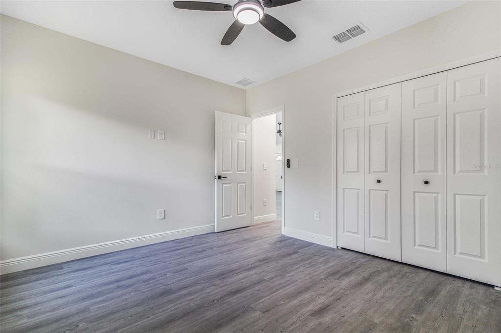 406 Ruby Avenue Deland, FL 32724 - Photo 8 of 23 an empty room with wooden floor chandelier fan and closet area