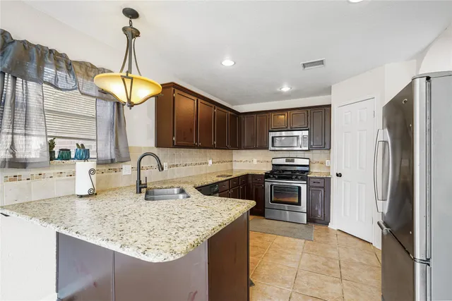 a kitchen with stainless steel appliances granite countertop a sink a stove and a refrigerator