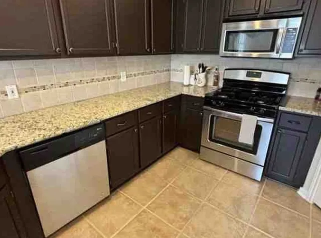 a kitchen with granite countertop a stove a microwave a sink and cabinets