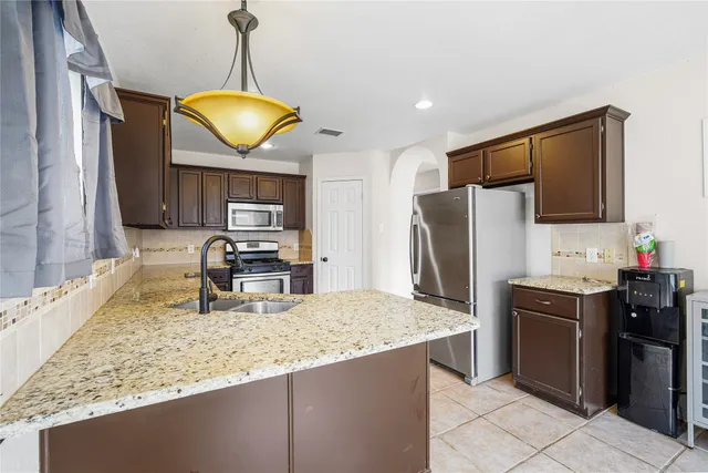 a kitchen with stainless steel appliances granite countertop a sink refrigerator and cabinets