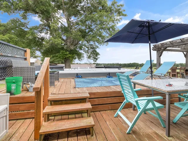 a view of a patio with table and chairs under an umbrella with wooden floor