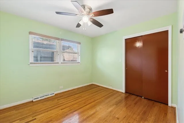 an empty room with wooden floor fan and windows