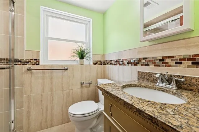 a bathroom with a granite countertop sink toilet and a mirror