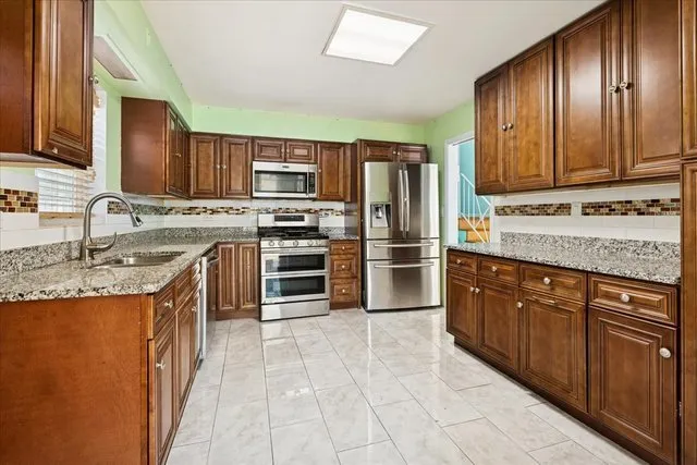 a kitchen with stainless steel appliances granite countertop a sink stove and refrigerator