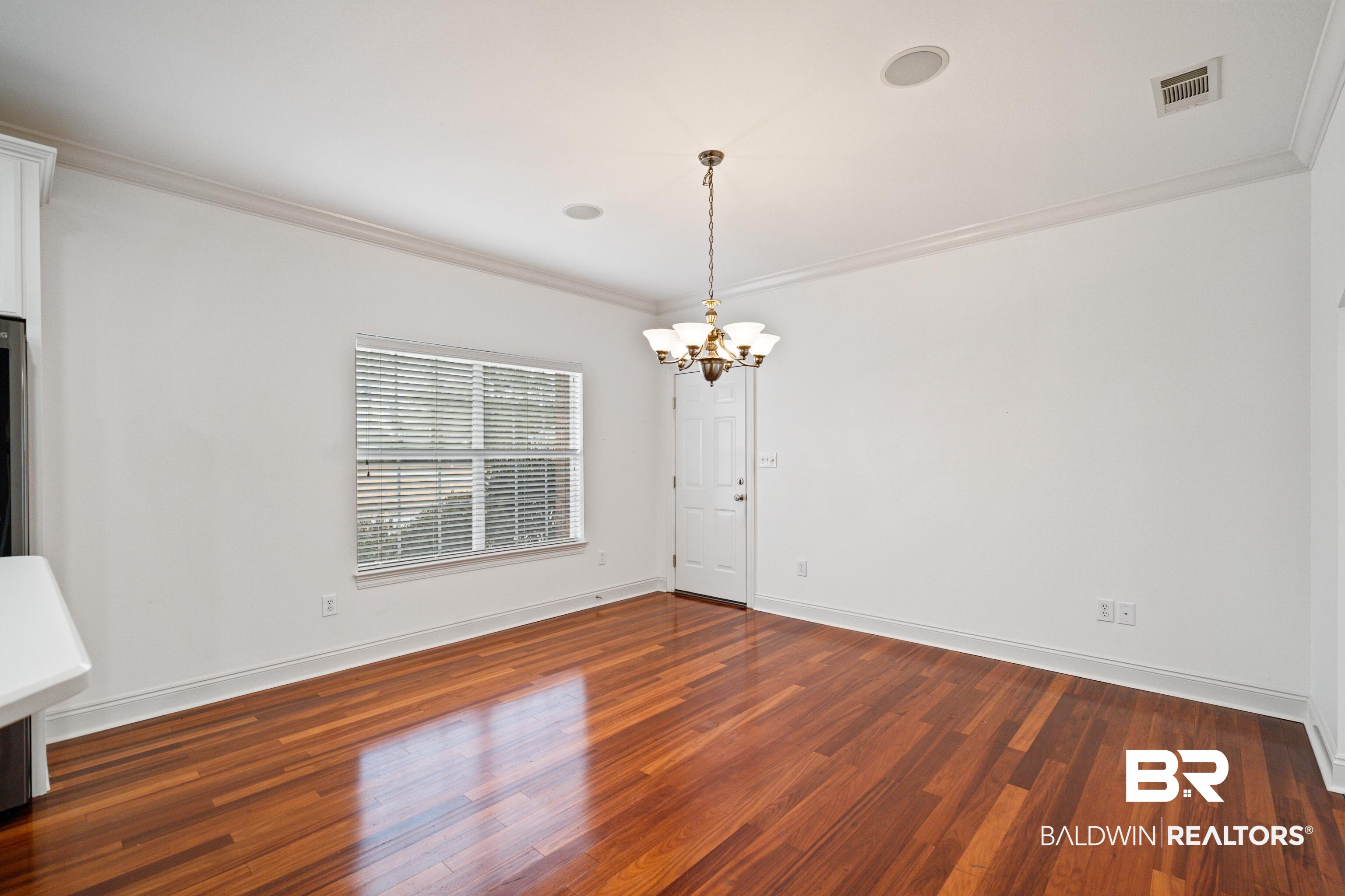 404 Savannah Lane Foley, AL 36535 - Photo 14 of 29 Spare room with ornamental molding, dark wood-type flooring, visible vents, and a notable chandelier