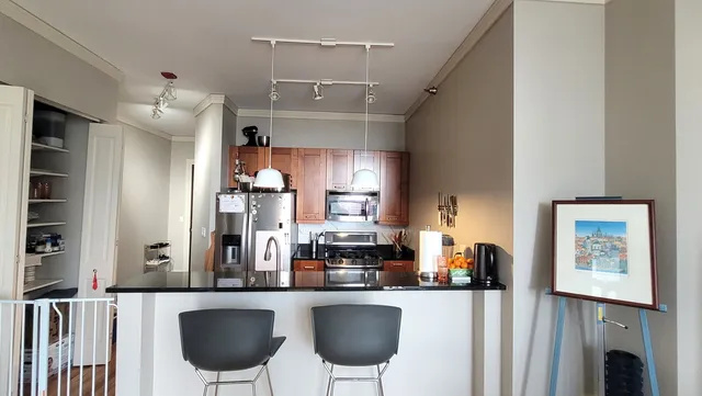 a kitchen with stainless steel appliances a dining table chairs and a refrigerator