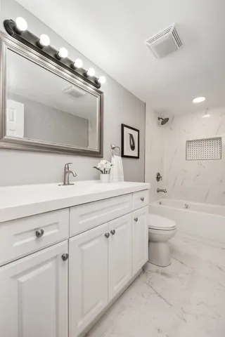 a bathroom with a double vanity sink a toilet and a tub