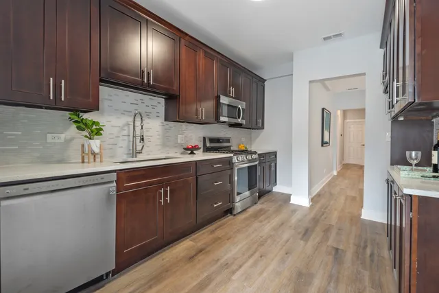 a kitchen with granite countertop wooden cabinets stainless steel appliances a sink and wooden floor
