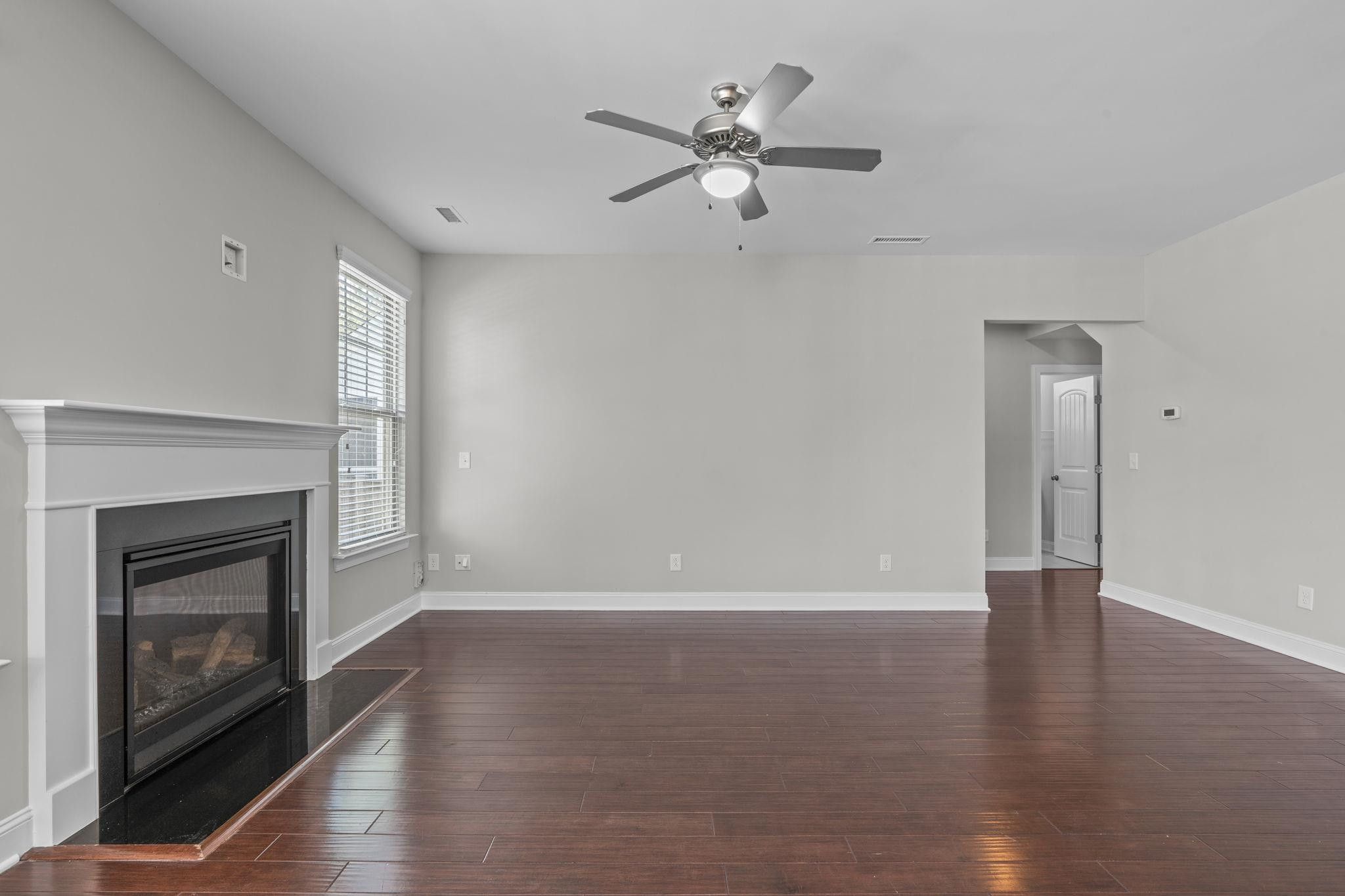 4240 Rockdell Hall Street Raleigh, NC 27616 - Photo 12 of 39 a view of an empty room with wooden floor fireplace and a window