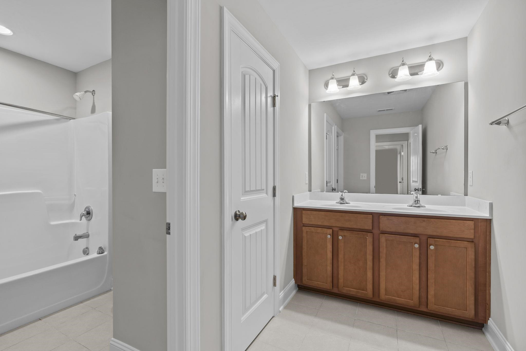 4240 Rockdell Hall Street Raleigh, NC 27616 - Photo 28 of 39 a spacious bathroom with a double vanity sink a large mirror and a bathtub