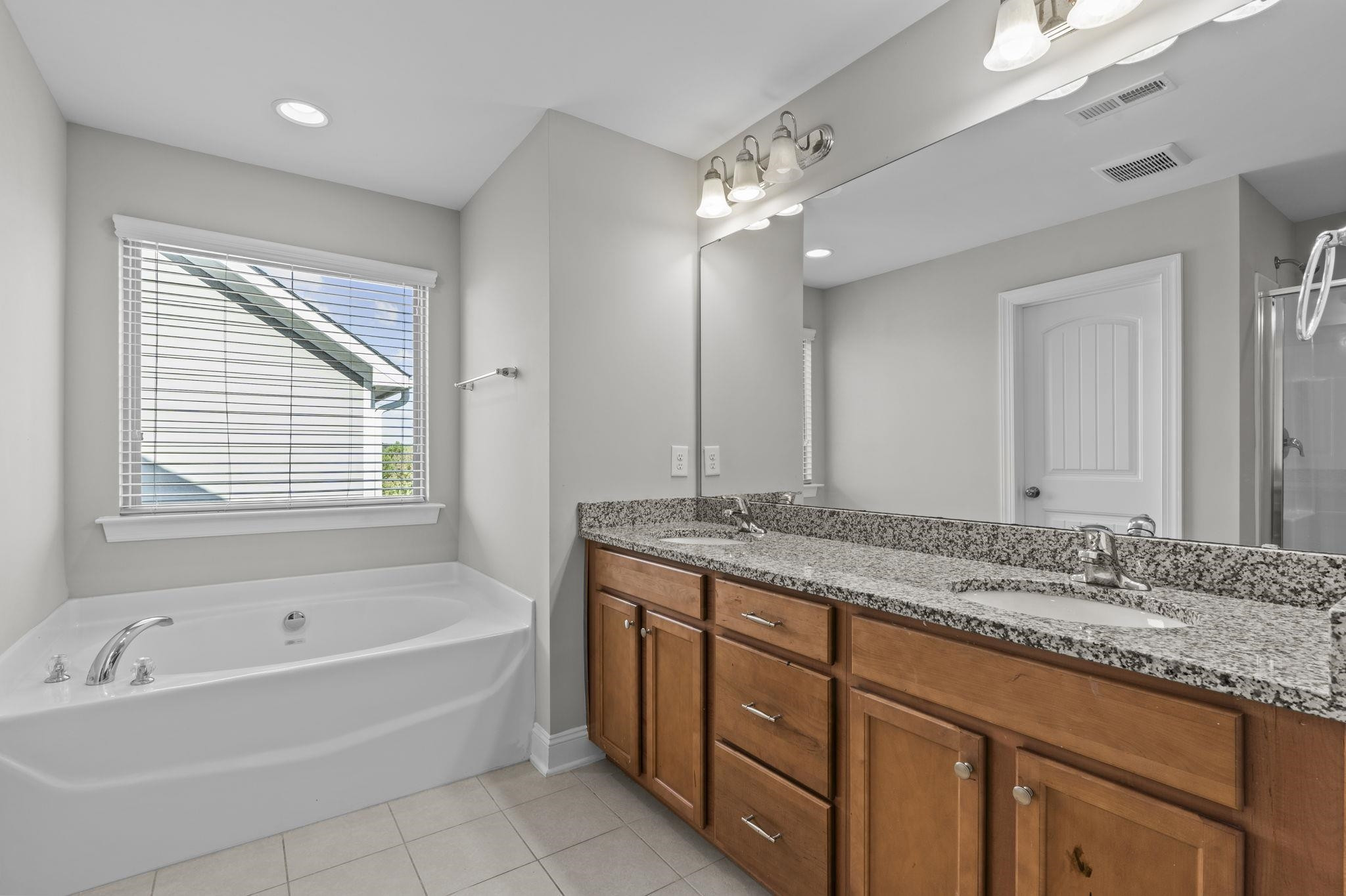 4240 Rockdell Hall Street Raleigh, NC 27616 - Photo 34 of 39 a bathroom with a granite countertop bathtub a sink and a large mirror