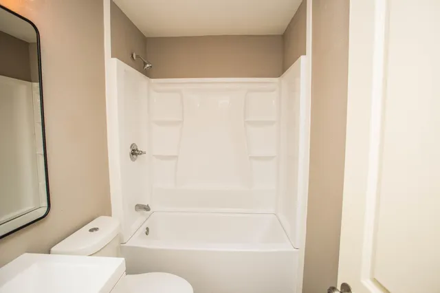 a bathroom with a toilet a sink and mirror