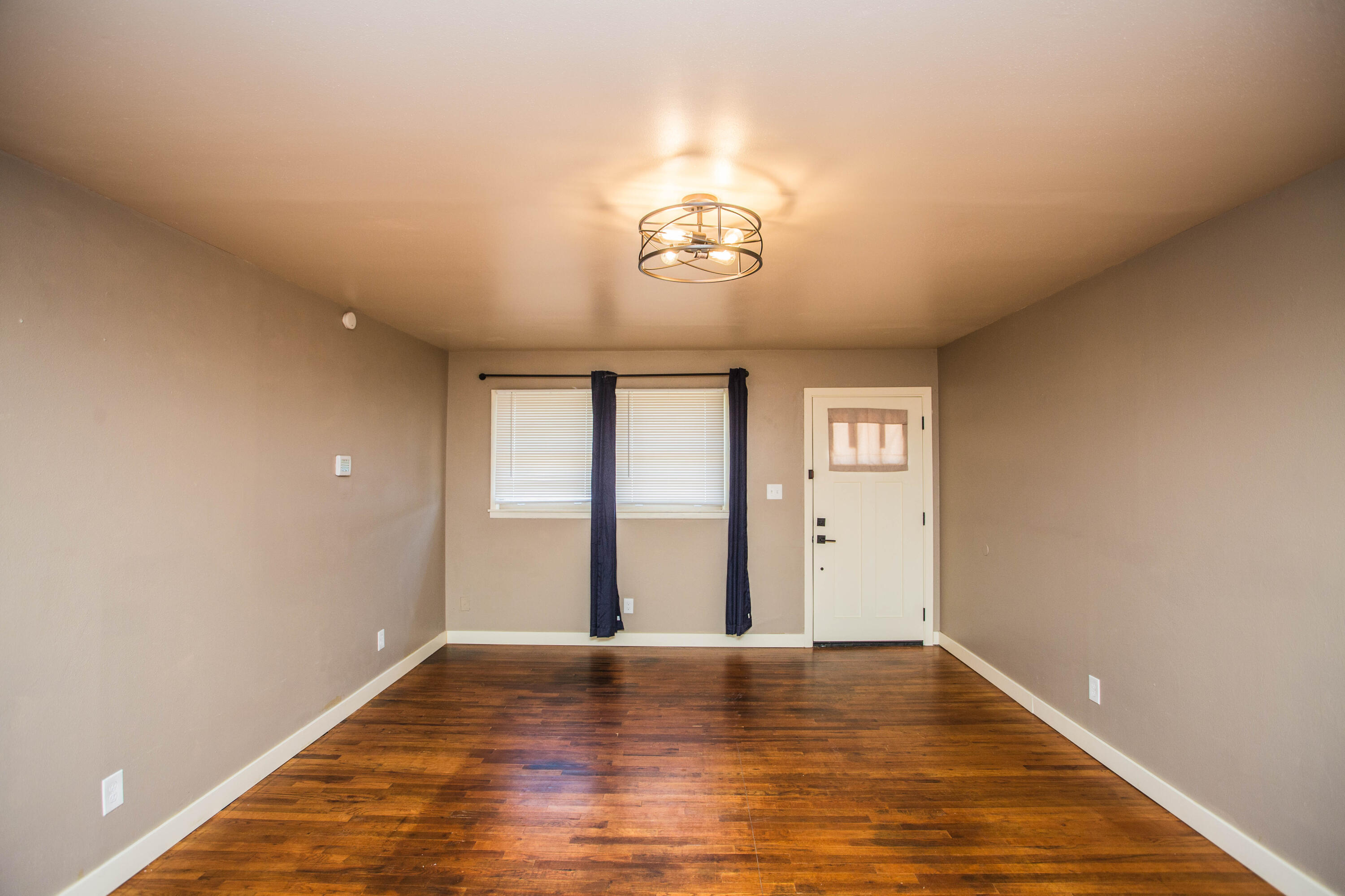 4402 29th Street, Unit B Lubbock, TX 79410 - Photo 3 of 23 a view of an empty room with wooden floor and a window