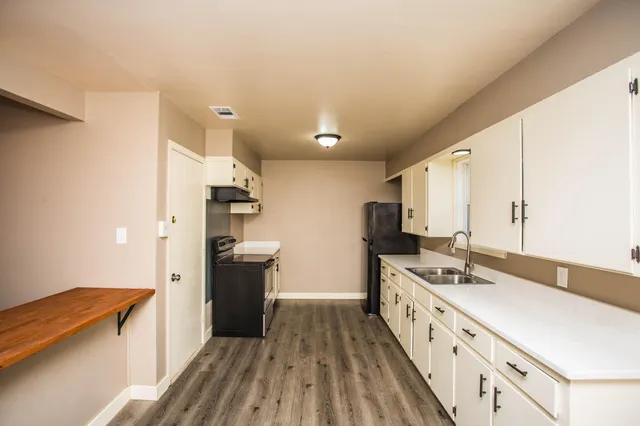 a kitchen with a sink a refrigerator and wooden floor