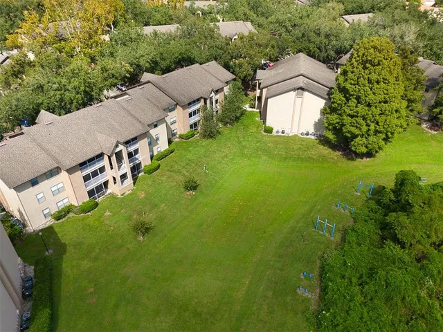 an aerial view of residential houses with outdoor space and trees