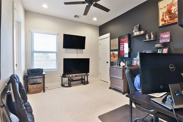 a work room with furniture a flat screen tv and a window