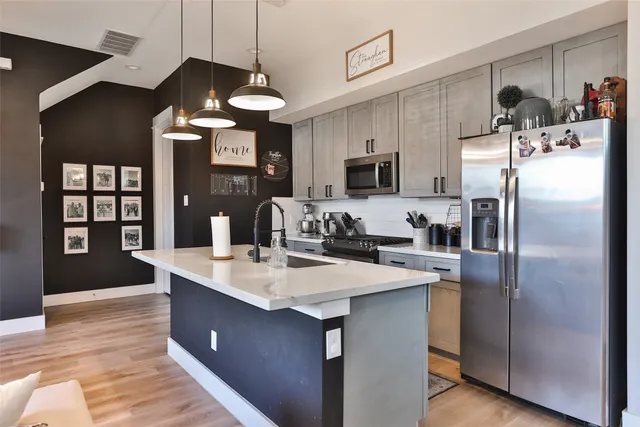 a kitchen with stainless steel appliances granite countertop a sink a refrigerator and a stove