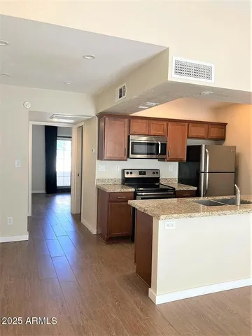 a kitchen with stainless steel appliances kitchen island granite countertop a stove a sink and a refrigerator