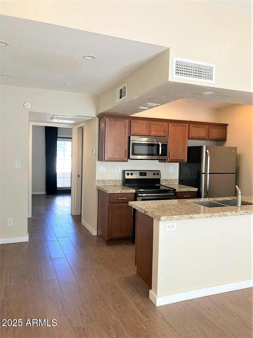 4540 North 44th Street, Unit 47 Phoenix, AZ 85018 - Photo 3 of 16 a kitchen with stainless steel appliances kitchen island granite countertop a stove a sink and a refrigerator