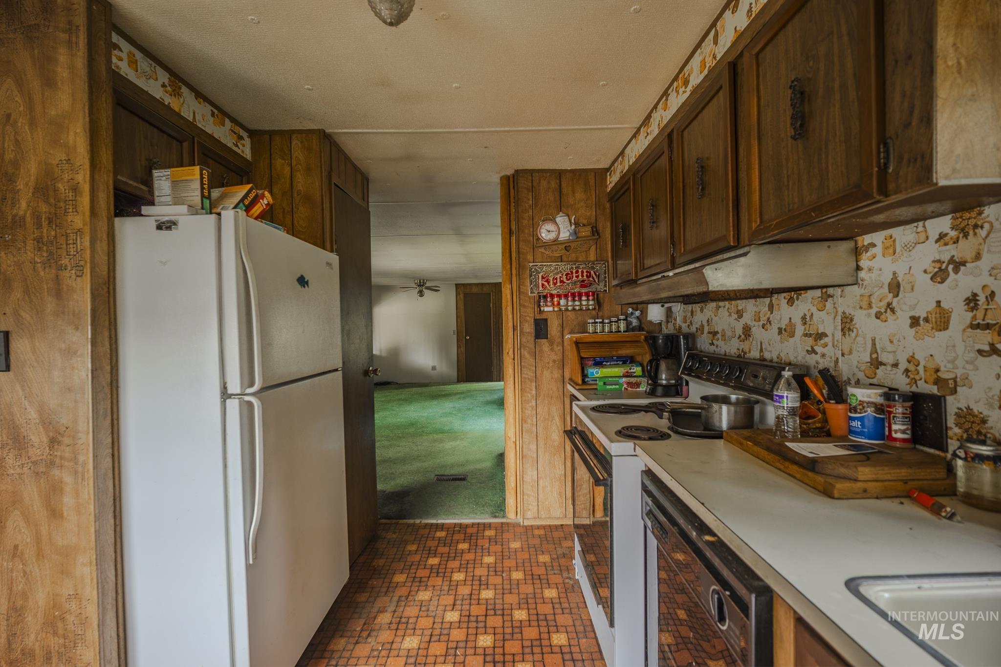 140 Ridgeway Drive Elk City, ID 83525 - Photo 16 of 47 Kitchen featuring white appliances, light countertops, dark brown cabinetry, and under cabinet range hood