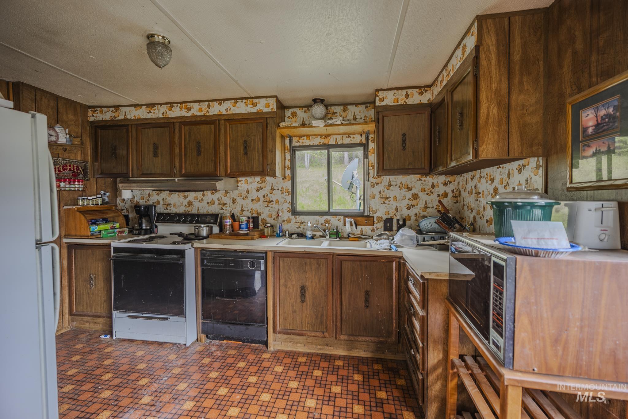 140 Ridgeway Drive Elk City, ID 83525 - Photo 17 of 47 Kitchen featuring light countertops, white appliances, dark floors, and dark brown cabinetry