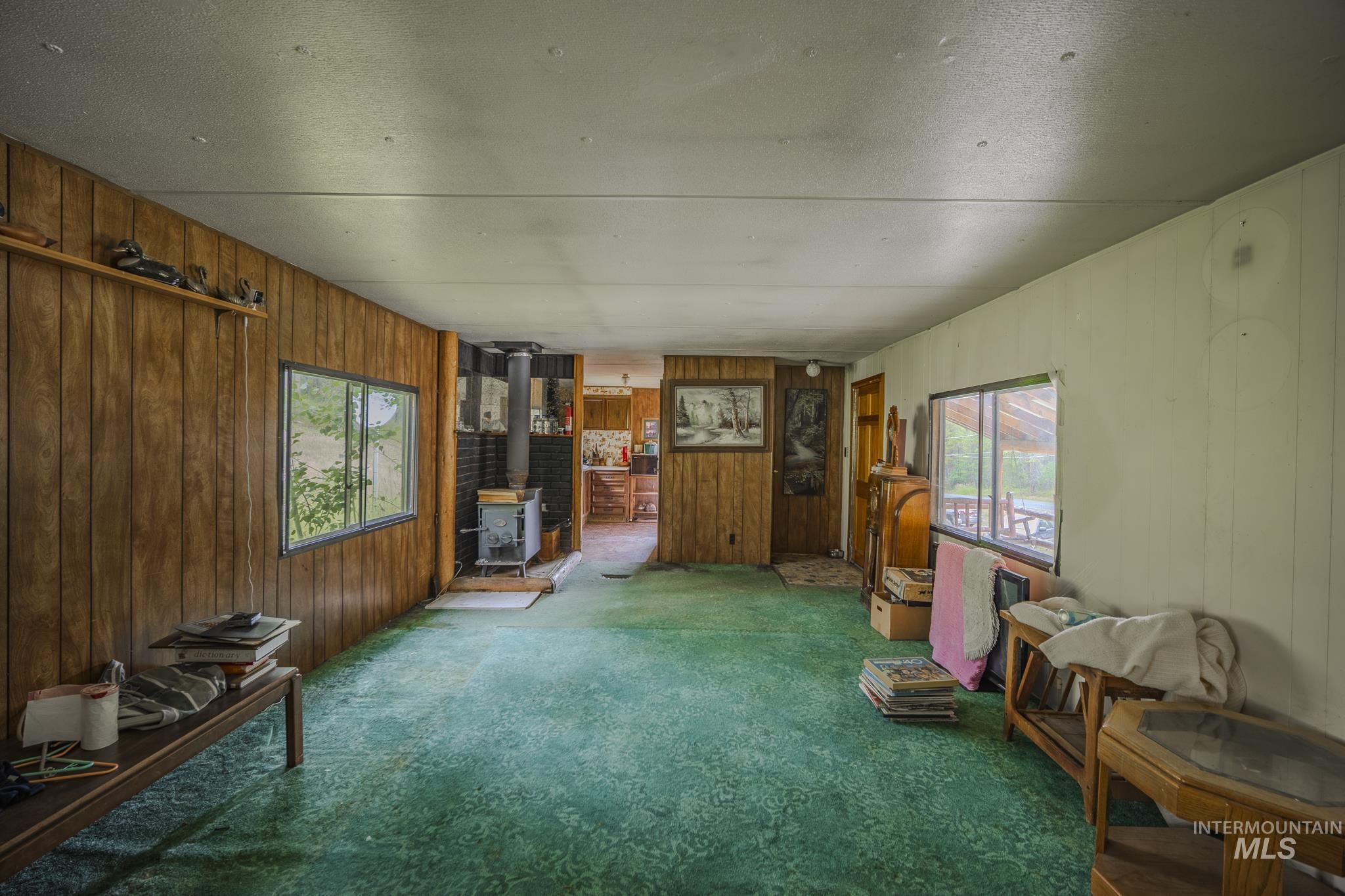 140 Ridgeway Drive Elk City, ID 83525 - Photo 20 of 47 Living area featuring a wood stove, wooden walls, and carpet