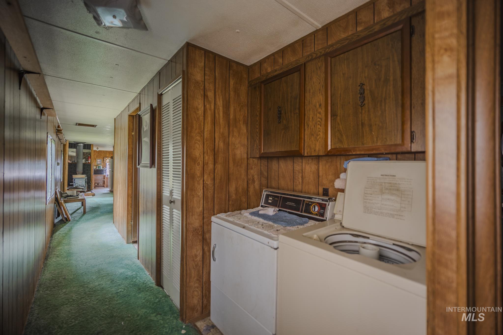 140 Ridgeway Drive Elk City, ID 83525 - Photo 21 of 47 Laundry room with light colored carpet, washing machine and dryer, wood walls, and cabinet space