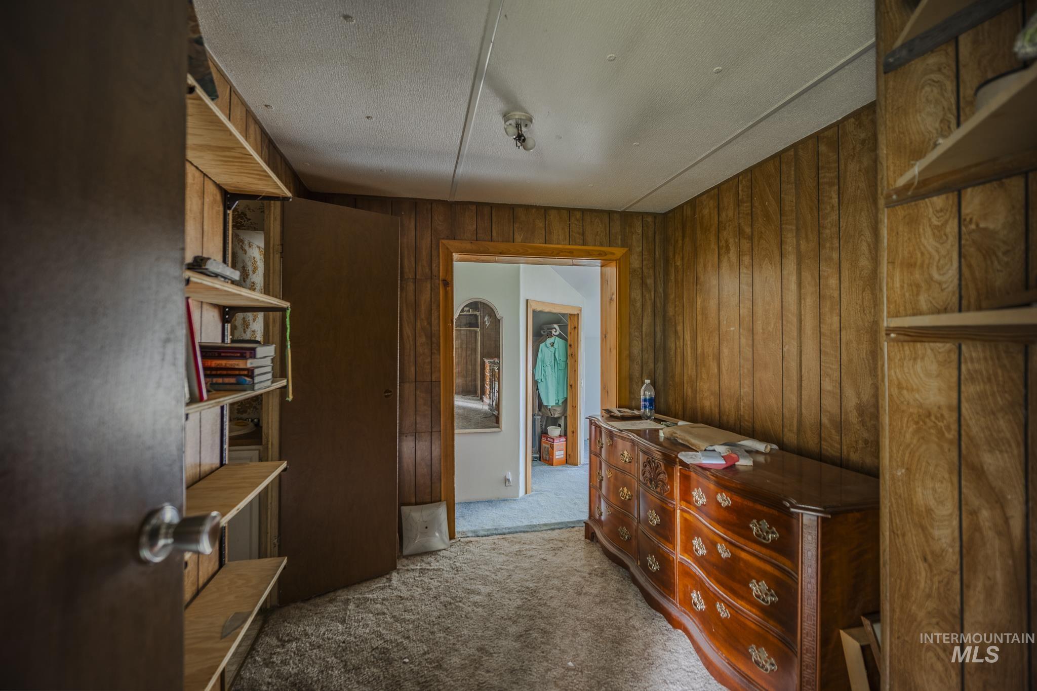 140 Ridgeway Drive Elk City, ID 83525 - Photo 23 of 47 Corridor with light colored carpet, wooden walls, and a textured ceiling