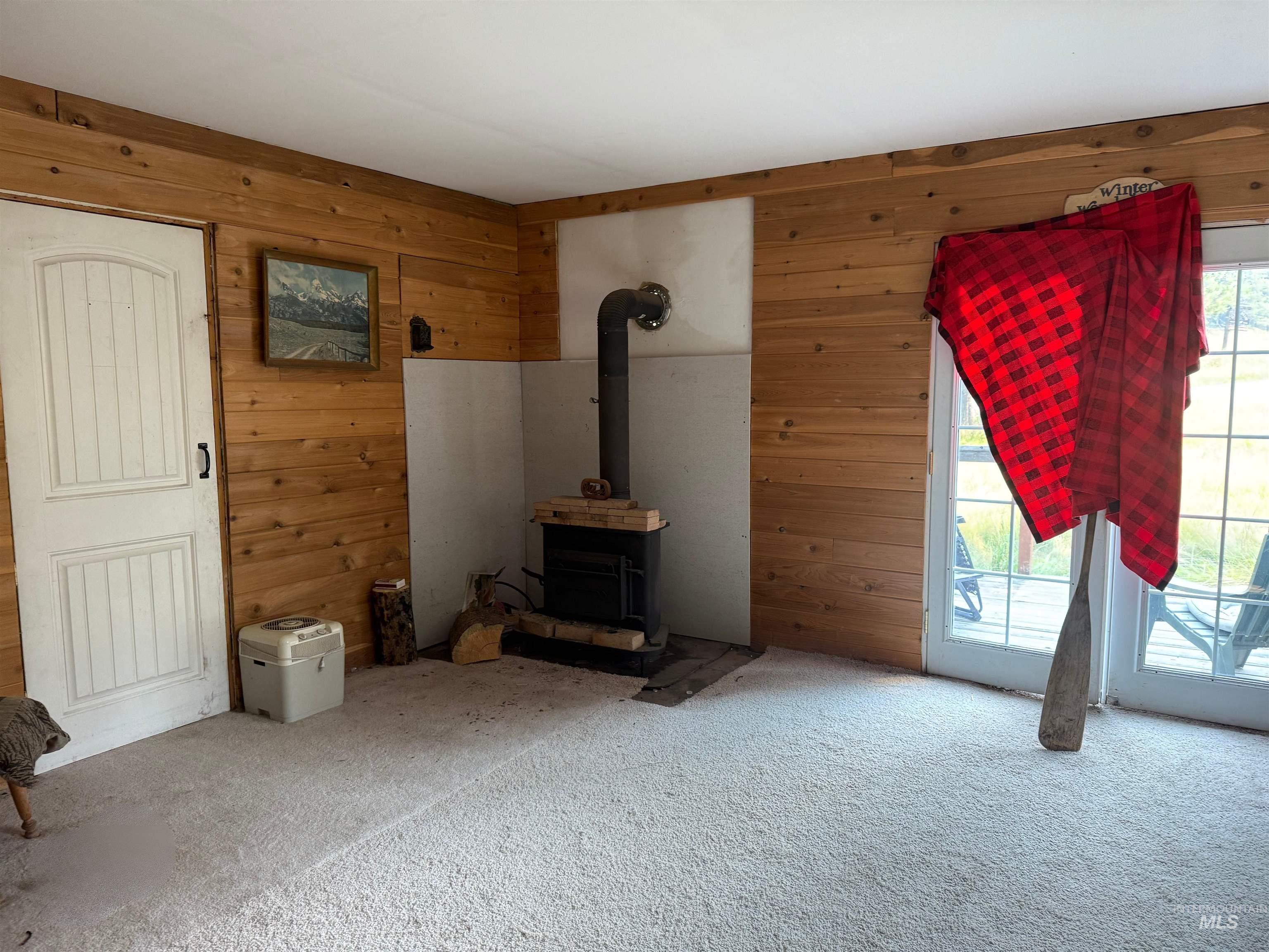140 Ridgeway Drive Elk City, ID 83525 - Photo 46 of 47 Unfurnished living room featuring wooden walls, carpet, and a wood stove