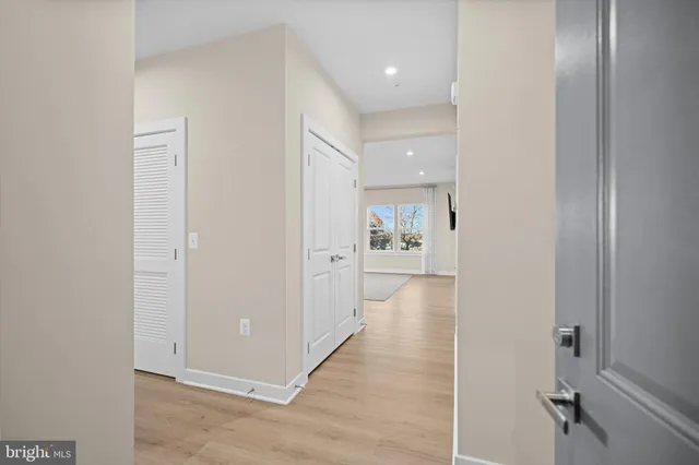 a view of a hallway with wooden floor and a bathroom