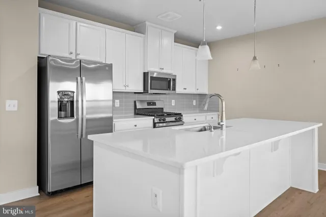 a kitchen with stainless steel appliances a refrigerator a sink a stove a microwave and island