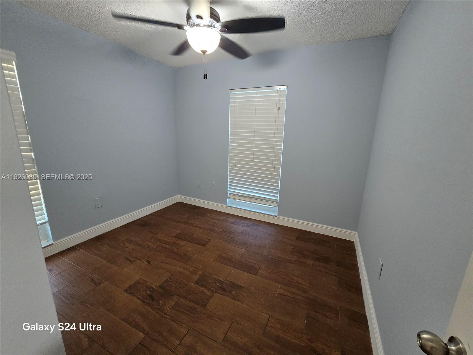 12364 Southwest 266th Terrace, Unit 12364 Homestead, FL 33032 - Photo 11 of 32 an empty room with wooden floor fan and windows