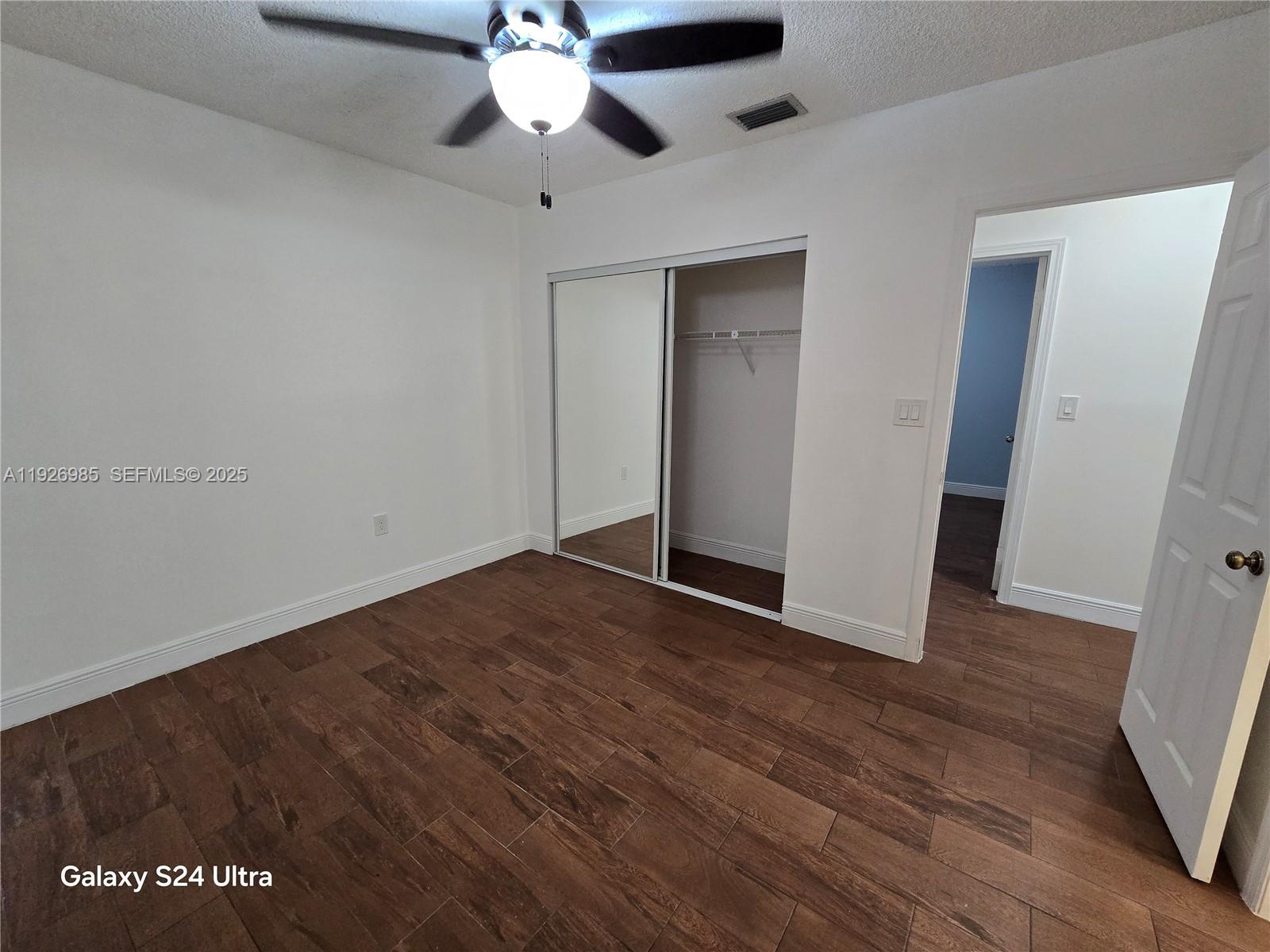 12364 Southwest 266th Terrace, Unit 12364 Homestead, FL 33032 - Photo 12 of 32 a view of an empty room with wooden floor and a ceiling fan