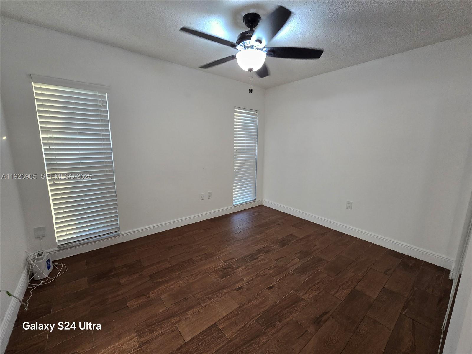 12364 Southwest 266th Terrace, Unit 12364 Homestead, FL 33032 - Photo 13 of 32 an empty room with wooden floor chandelier fan and windows