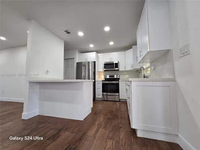 a kitchen with granite countertop a refrigerator and a stove top oven