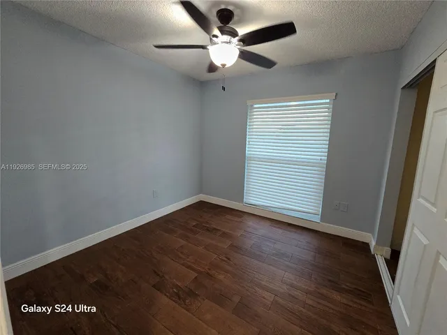an empty room with wooden floor fan and window