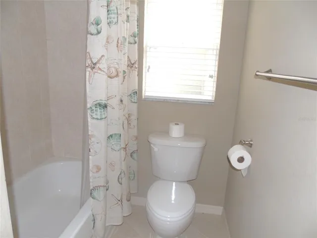 en empty room with chandelier fan and windows