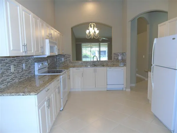 a bathroom with a granite countertop sink a refrigerator and a mirror