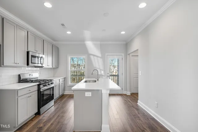 a large white kitchen with wooden floors and stainless steel appliances