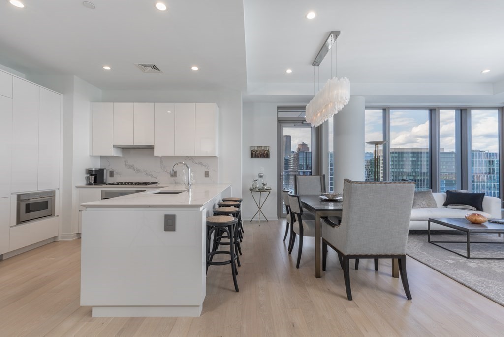 133 Seaport Boulevard, Unit 1908 Boston, MA 02210 - Photo 7 of 34 a kitchen with a table chairs stove and cabinets
