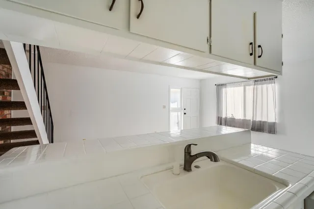 a kitchen with kitchen island a stove a sink and white cabinets