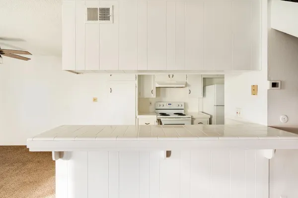 a kitchen with kitchen island a stove a sink and white cabinets