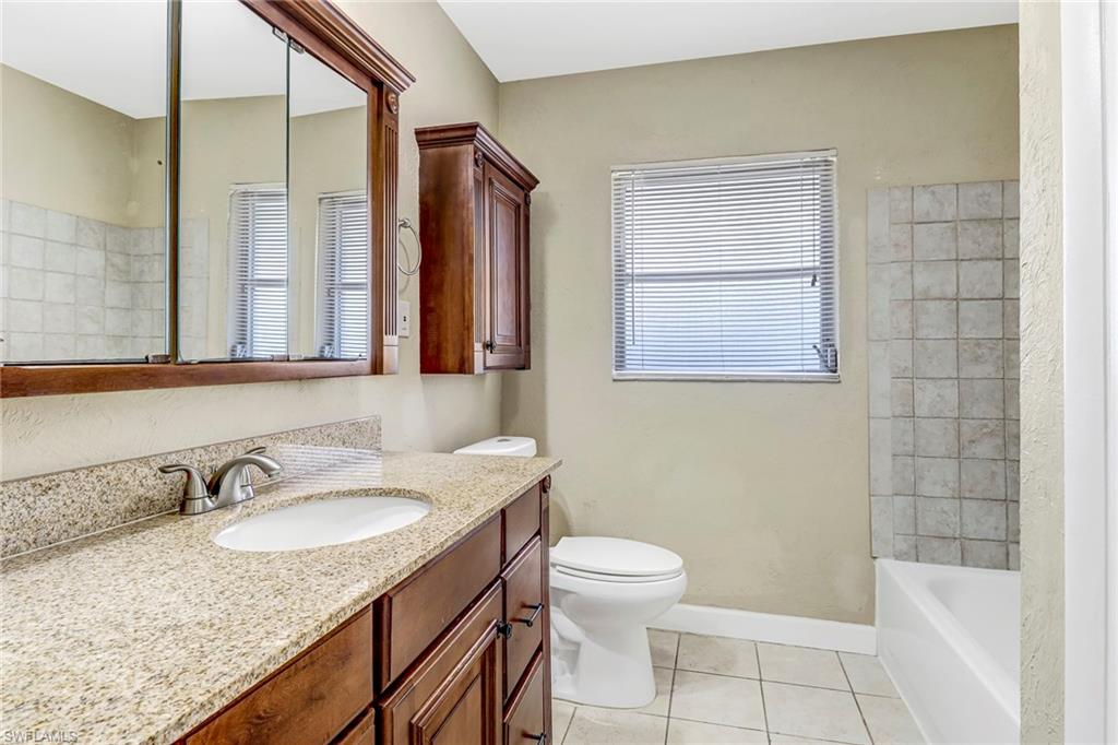 189 Mentor Drive Naples, FL 34110 - Photo 17 of 25 a bathroom with a granite countertop sink toilet and shower