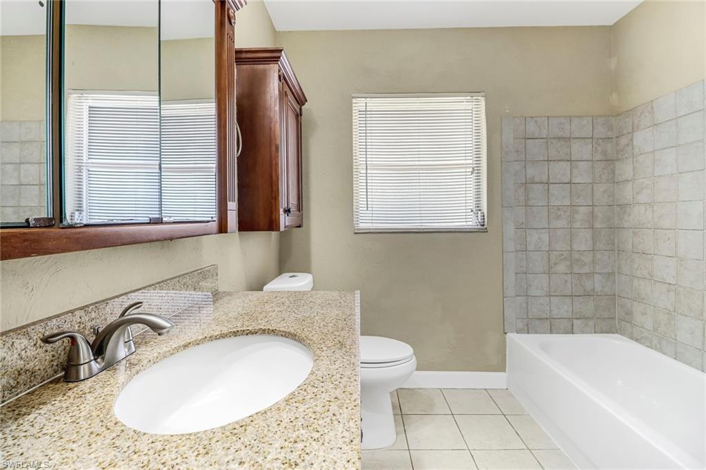 189 Mentor Drive Naples, FL 34110 - Photo 18 of 25 a bathroom with a granite countertop sink a toilet a mirror and bathtub