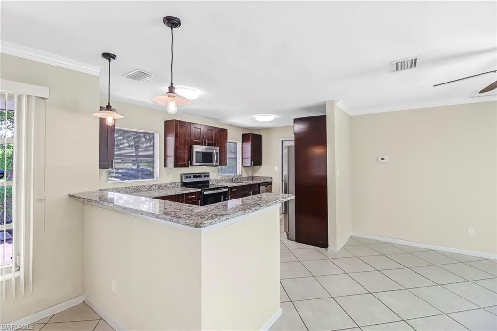 189 Mentor Drive Naples, FL 34110 - Photo 10 of 25 a kitchen with stainless steel appliances granite countertop a sink a stove a refrigerator and island