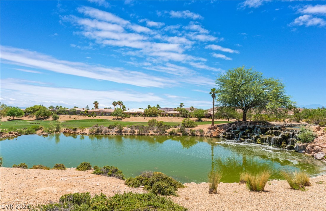 5389 Progresso Street Las Vegas, NV 89135 - Photo 36 of 41 A tranquil golf course vista unfolds, featuring a shimmering lake with a cascading waterfall, framed by lush desert landscaping.