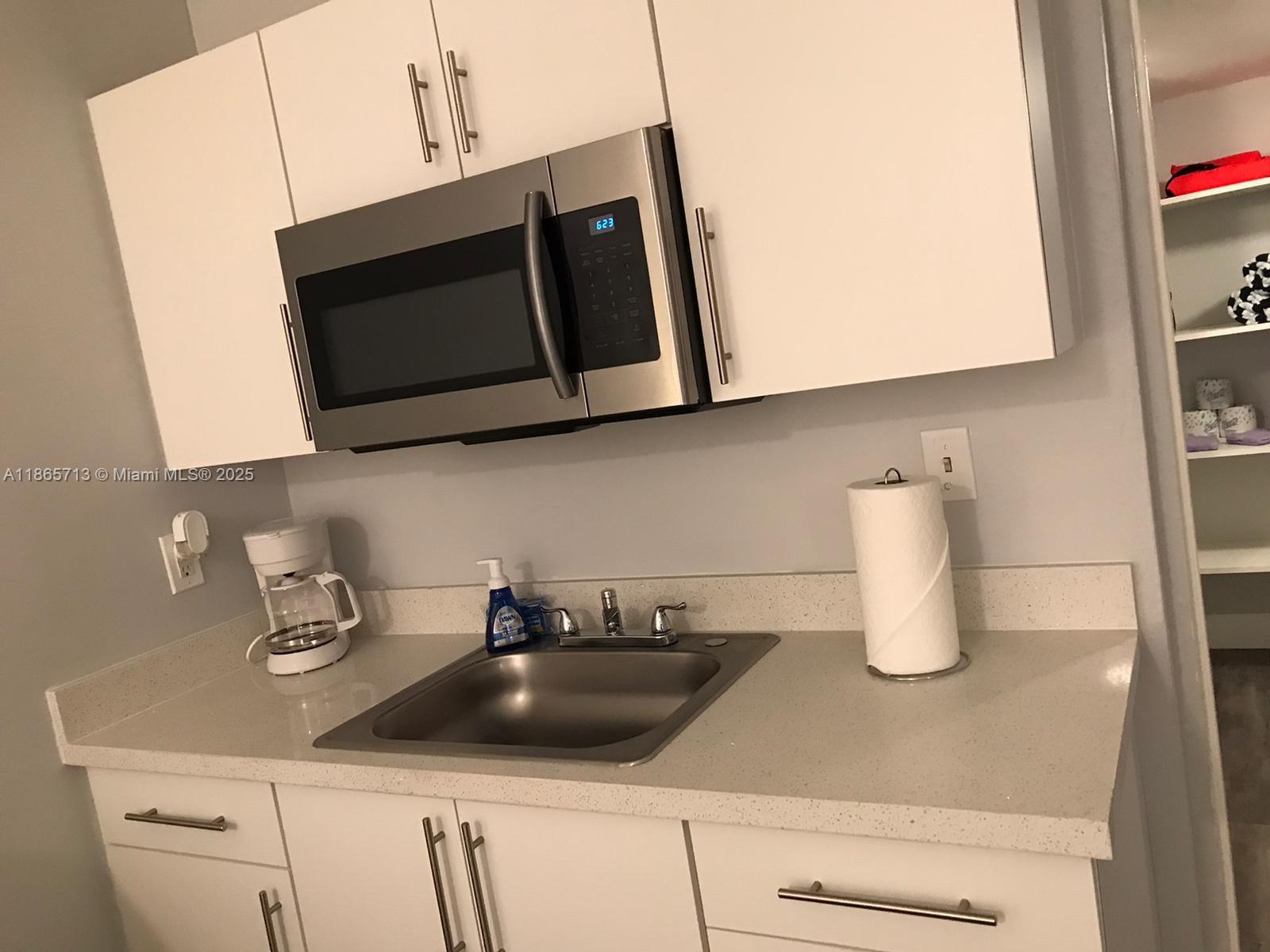 26 Diplomat Parkway, Unit 2215 Hallandale Beach, FL 33009 - Photo 5 of 12 a kitchen with a sink and a microwave