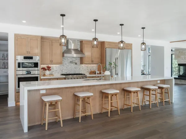 a large kitchen with kitchen island a large counter top space and stainless steel appliances
